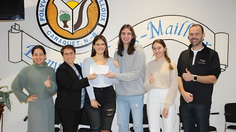 Eine Gruppe Schüler steht vor einem farbenfrohen Wandbild auf dem Campus der Polyvalente Louis-Mailloux.