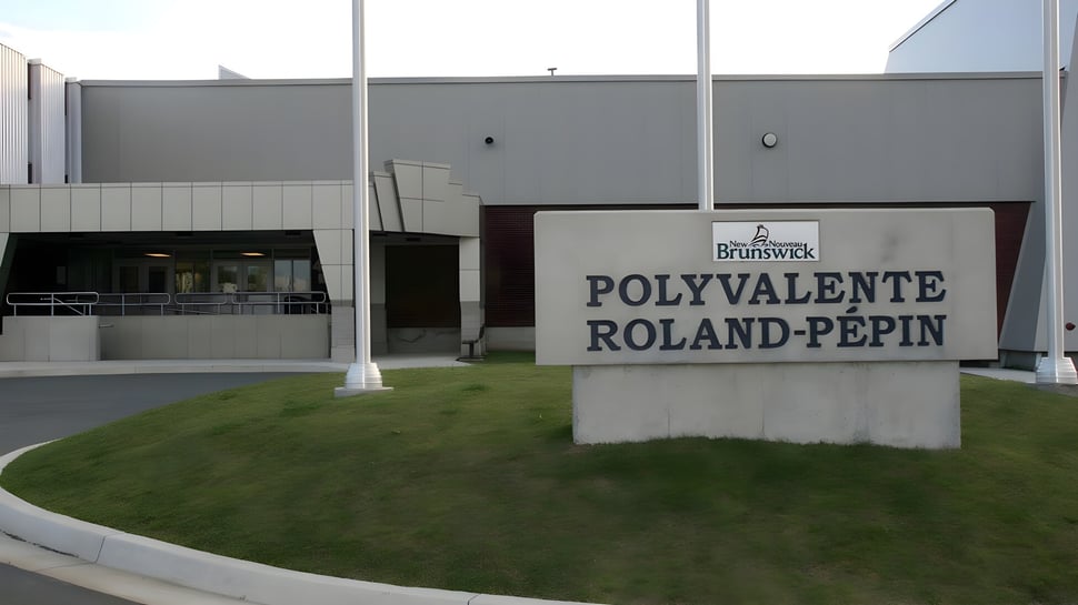 Das moderne Gebäude der Polyvalente Roland-Pépin mit großem Eingangsschild und einer Rasenfläche davor.