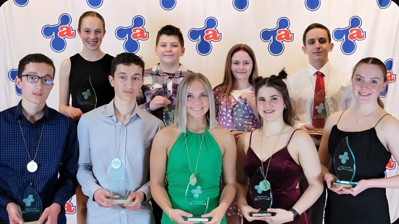 Eine Gruppe von Schülerinnen und Schülern der Polyvalente Thomas-Albert posiert gemeinsam vor einem Logo.