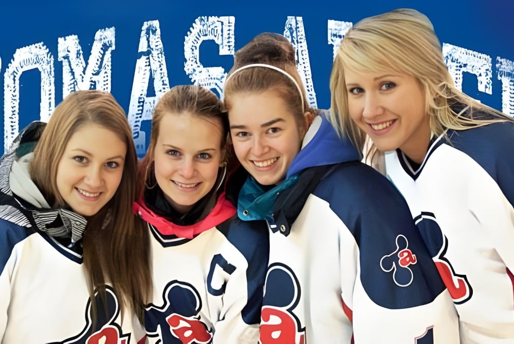 Vier Schülerinnen der Polyvalente Thomas-Albert tragen identische Sporttrikots und stehen vor einem blauen Hintergrund mit dem Schriftzug Hockey.