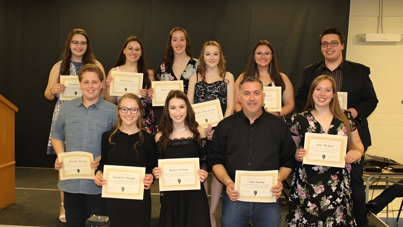 Schülerinnen und Schüler der Polyvalente W.-A.-Losier halten Zertifikate und posieren für ein Gruppenfoto in formeller Umgebung.