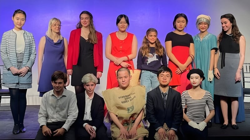 Eine Gruppe von Schülerinnen und Schülern steht und sitzt auf einer Bühne mit lila Hintergrund auf der Pomfret School.