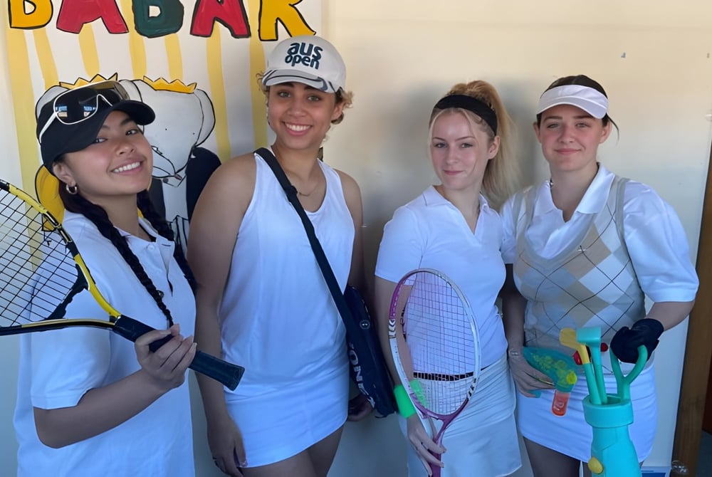 Vier Schülerinnen der Port Hacking High School posieren gemeinsam vor dem farbenfrohen Badark Schild.