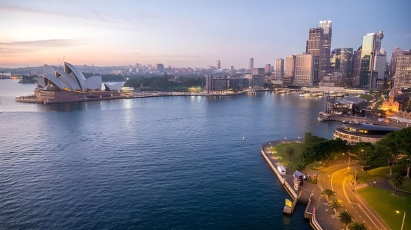 Ein beeindruckender Blick auf die Skyline mit dem Sydney Opera House im Vordergrund bei Sonnenuntergang, nahe der Port Hacking High School.