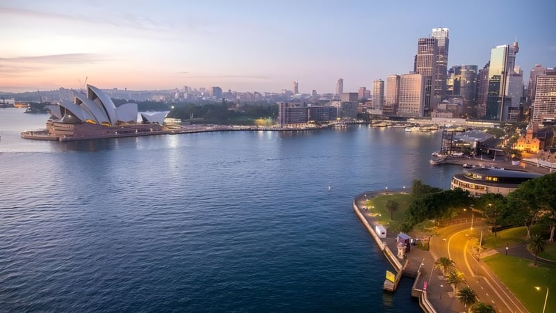 Ein beeindruckender Blick auf die Skyline mit dem Sydney Opera House im Vordergrund bei Sonnenuntergang, nahe der Port Hacking High School.