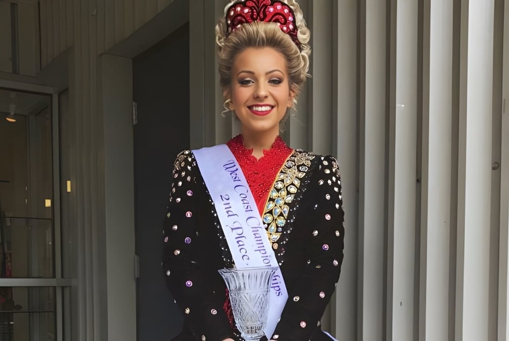 Eine Frau mit einer kunstvollen Krone steht vor einem Gebäude mit Säulen auf dem Campus der Port Moody Secondary School.