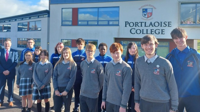 Eine Gruppe Schüler in Schuluniformen steht vor dem Gebäude des Portlaoise College.