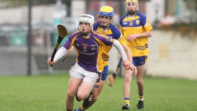 Drei Schülerinnen und Schüler von Portlaoise College spielen eine Sportart auf einem grasbewachsenen Feld.