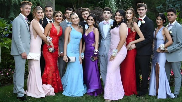 Eine Gruppe von Schülerinnen und Schülern der Portmarnock Community School posiert gemeinsam in formeller Kleidung im Garten.