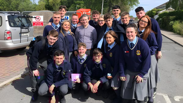 Eine Gruppe Schüler in Schuluniformen steht und sitzt im Außenbereich der Portmarnock Community School.