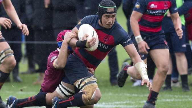 Ein Rugbyspieler der Portmarnock Community School trägt den Ball während eines Tacklings auf dem Spielfeld.