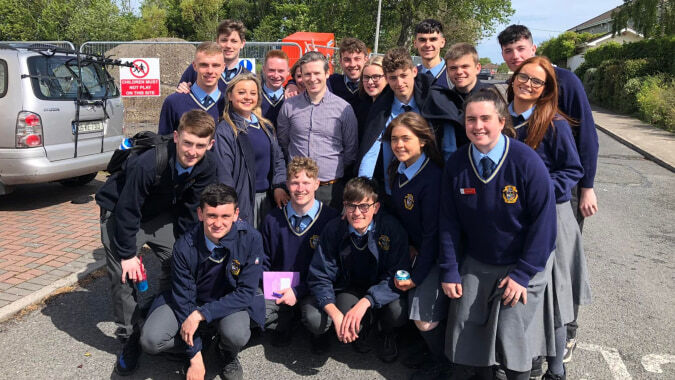 Eine Gruppe von Schülern der Portmarnock Community School steht und sitzt gemeinsam vor einem Van im Freien.