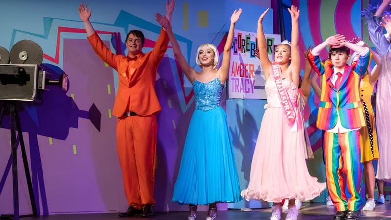 Eine Gruppe von Schülerinnen und Schülern des Portumna Community College präsentiert sich in bunten Kostümen auf einer lebhaften Bühne.