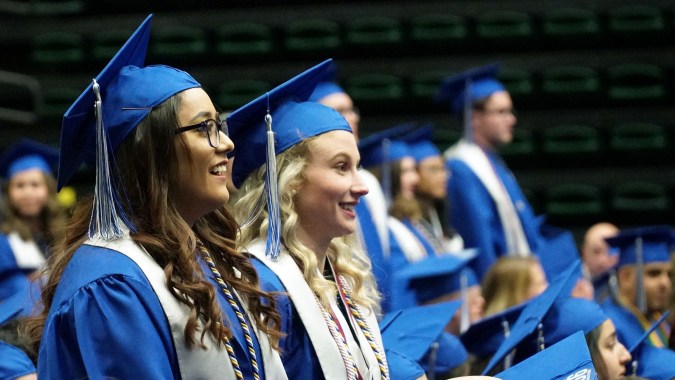 Eine Gruppe Absolventinnen und Absolventen in blauen Talaren und Hüten steht zusammen im Poudre School District.