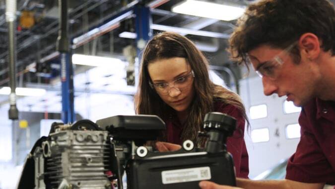 Zwei Personen untersuchen eine Maschine in einer Werkstatt im Poudre School District.