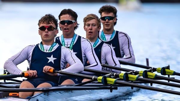 Eine Gruppe von Ruderern in einheitlichen Trikots und Sonnenbrillen beim Rudern auf dem Wasser bei Presentation Brothers College.