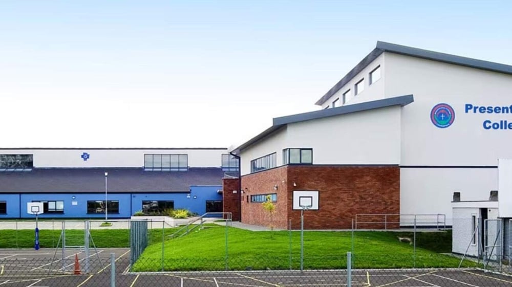 Das moderne mehrstöckige Schulgebäude des Presentation College Carlow mit blau-weißer Fassade steht auf einem grasbewachsenen Gelände.