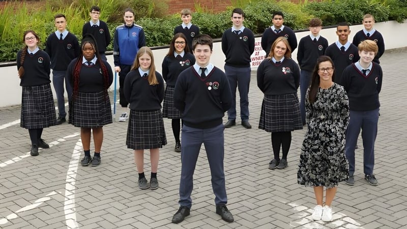 Eine Gruppe Schülerinnen und Schüler des Presentation College Carlow steht zusammen auf einem gepflasterten Außenbereich mit Grünflächen.