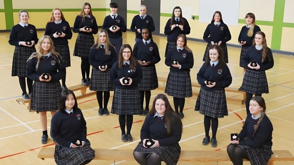 Eine Gruppe Schülerinnen und Schüler des Presentation College Carlow steht in der Turnhalle in ihrer Schuluniform.