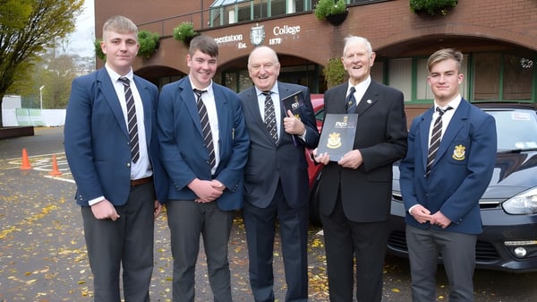 Eine Gruppe von Schülern in Schuluniformen steht vor dem Backsteingebäude der Presentation College Galway.