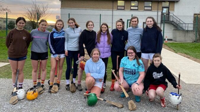 Eine Gruppe junger Athletinnen posiert vor einem Gebäude auf dem Campus der Presentation Secondary School in Cork.