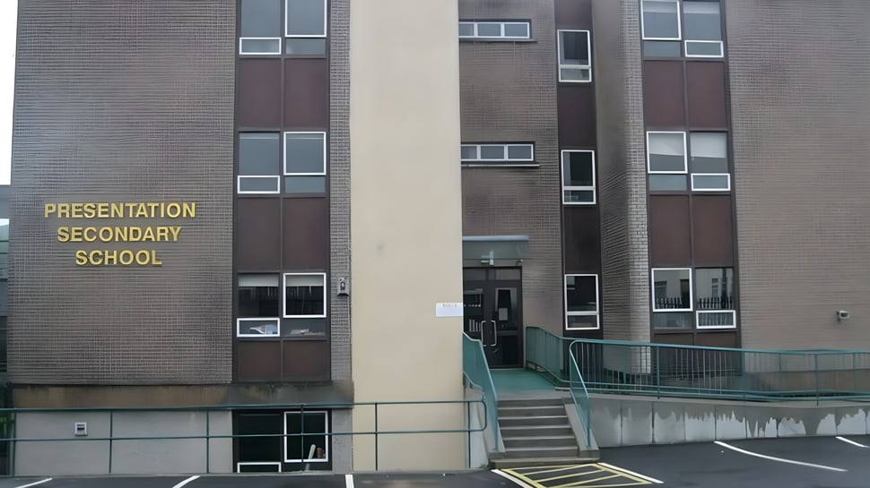 Das mehrstöckige Backsteingebäude der Presentation Secondary School in Cork mit einem umliegenden Parkplatz ist zu sehen.