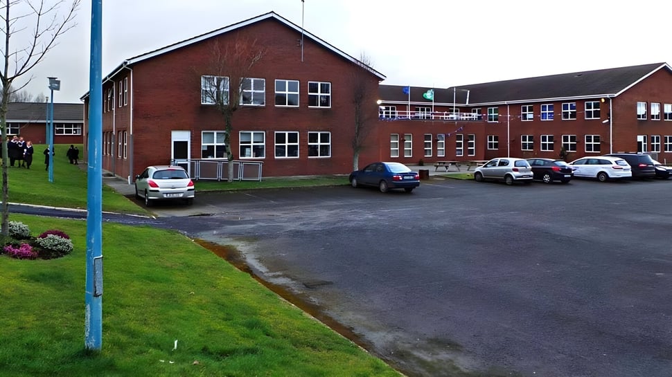 Das Backsteingebäude der Presentation Secondary School in Kilkenny mit Parkplätzen und Fahrzeugen im Vordergrund.
