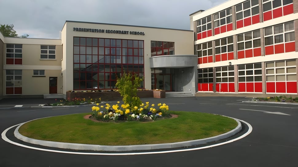 Das moderne mehrstöckige Gebäude der Presentation Secondary School in Tipperary mit großen Fenstern und einem runden Blumenbeet im Vordergrund.