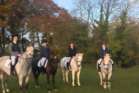 Schüler der Presentation Secondary School in Tipperary reiten im Freien auf Pferden in landschaftlicher Umgebung.