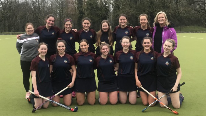 Eine Gruppe junger Schülerinnen der Presentation Secondary School (Thurles) posiert auf einem Grasfeld in Sportuniformen.