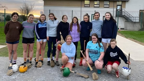 Eine Gruppe weiblicher Schülerinnen posiert mit Sportgerät draußen vor einem Gebäude auf dem Campus der Presentation Secondary School in Cork.