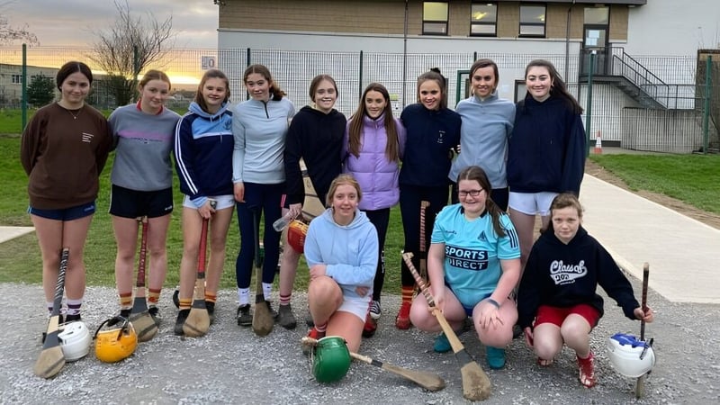 Eine Gruppe weiblicher Schülerinnen posiert mit Sportgerät draußen vor einem Gebäude auf dem Campus der Presentation Secondary School in Cork.
