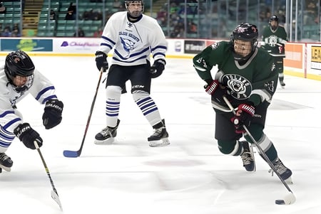 Zwei Eishockeyspieler in Teamtrikots kämpfen auf dem Eis vor Zuschauern bei der Prince George Secondary School.