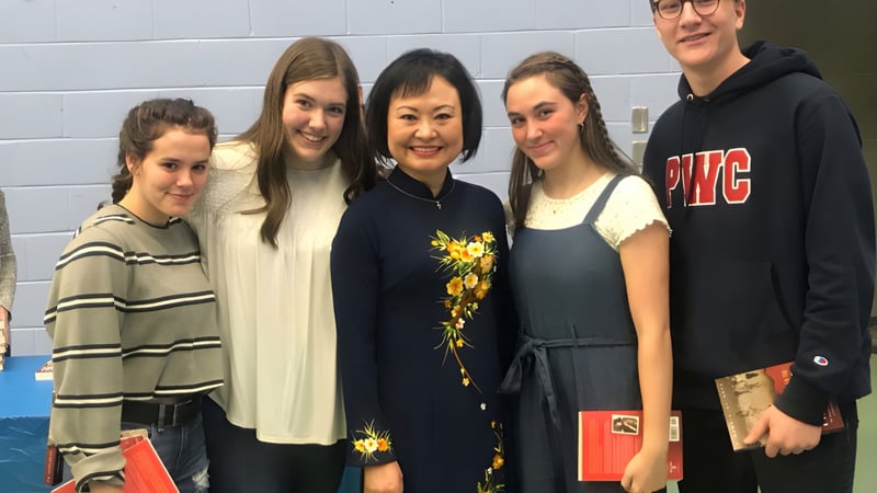 Fünf Schülerinnen und Schüler posieren gemeinsam vor einer blauen Wand auf dem Campus des Prince of Wales Collegiate.