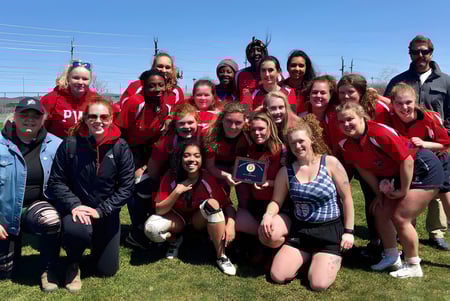 Eine Gruppe von Schülerinnen in roten Uniformen steht auf einer Wiese auf dem Gelände des Prince of Wales Collegiate.