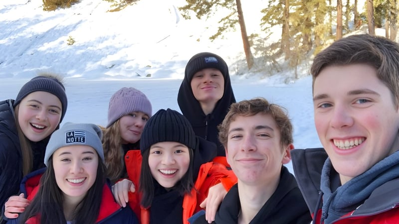 Schüler der Prince of Wales Secondary School stehen im verschneiten Wald in warmer Winterkleidung zusammen.