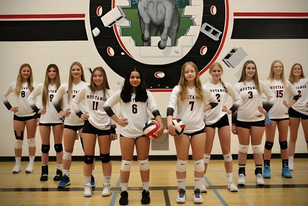 Eine Gruppe weiblicher Volleyballspielerinnen der Princess Margaret Secondary School steht in der Sporthalle zusammen.
