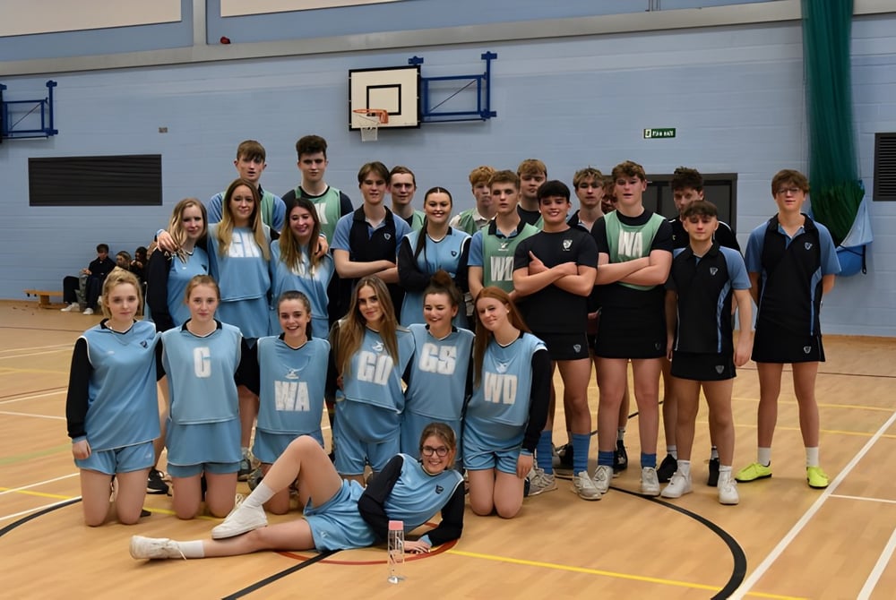 Eine Gruppe Schüler des Prior Park College posiert in der Sporthalle mit Basketballkörben im Hintergrund.