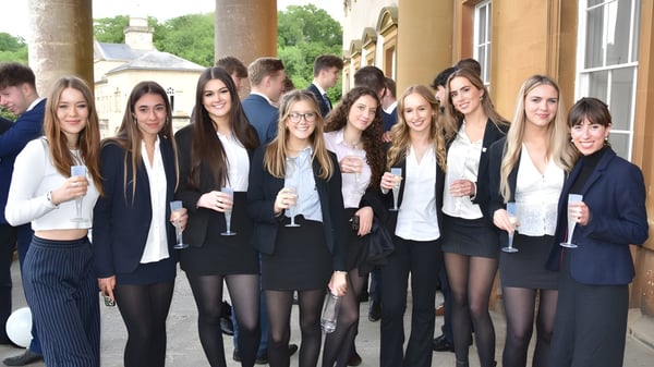Eine Gruppe junger Frauen in formeller Kleidung steht vor einem historischen Gebäude auf dem Campus von Prior Park College.