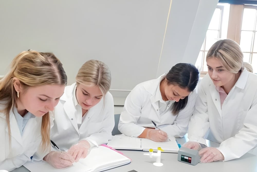 Vier Schülerinnen der Prior's Field Schule arbeiten konzentriert an einem Experiment im Labor.