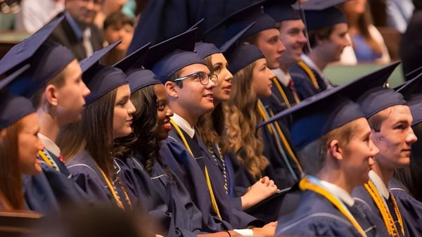 Eine Gruppe von Absolventinnen und Absolventen der Providence Christian Academy steht bei einer feierlichen Zeremonie in akademischer Kleidung zusammen.