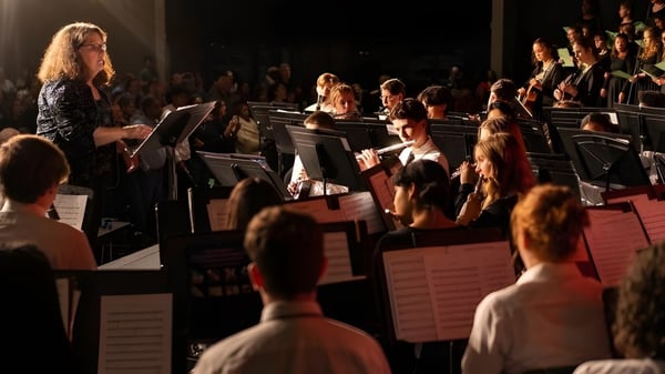 Ein großes Orchester spielt auf der Bühne der Providence Christian Academy vor einem sichtbaren Publikum.