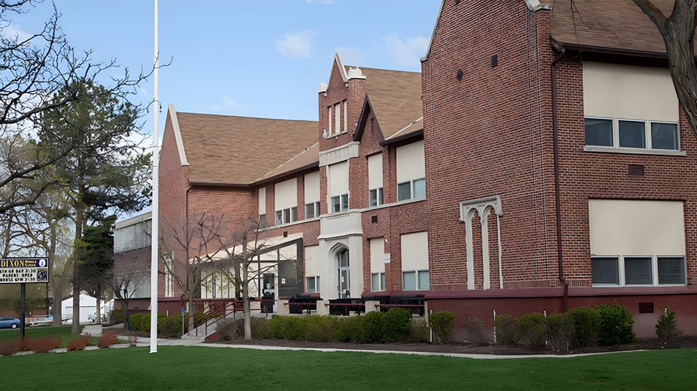Das Backsteingebäude mit markanter Architektur auf dem Campus des Provo City School District ist von einer Grünfläche und Bäumen umgeben.