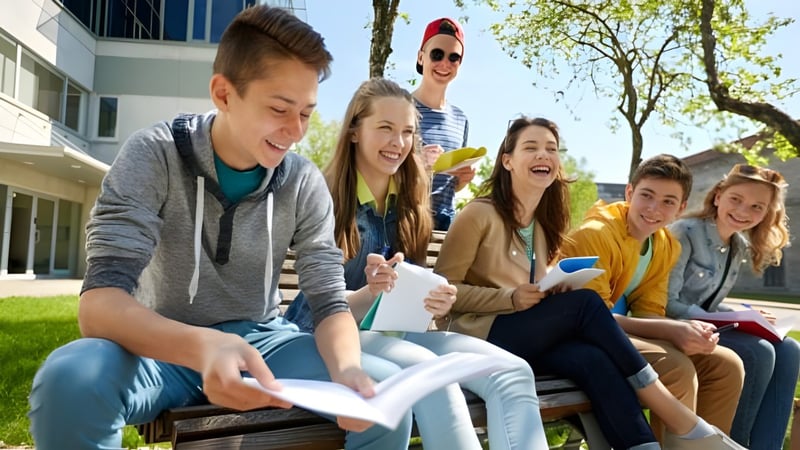 Eine Gruppe von Schülerinnen und Schülern sitzt auf einer Bank und unterhält sich auf dem Campus der Provo City School District.