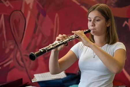 Eine Schülerin der The Purcell School for Young Musicians spielt Flöte auf einer Bühne mit rotem Hintergrund.