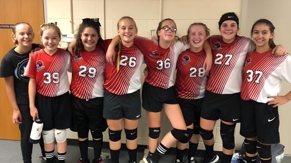 Eine Gruppe junger Sportlerinnen posiert gemeinsam in der Sportumkleide der Quad Cities Christian School.