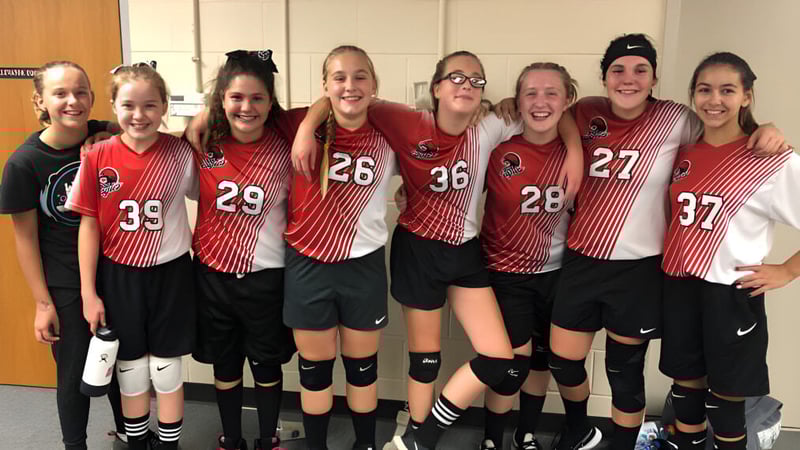 Eine Gruppe junger Sportlerinnen posiert gemeinsam in der Sportumkleide der Quad Cities Christian School.