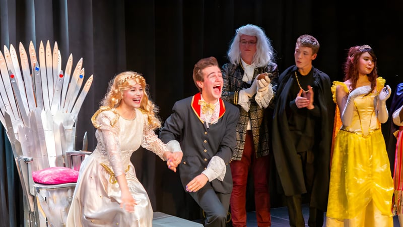 Schüler der Québec High School stehen in bunten Kostümen auf einer Bühne vor einem Vorhang.