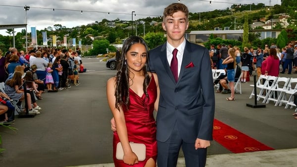 Schüler der Queechy High School posieren in formeller Kleidung auf dem roten Teppich vor einer Menschenmenge.