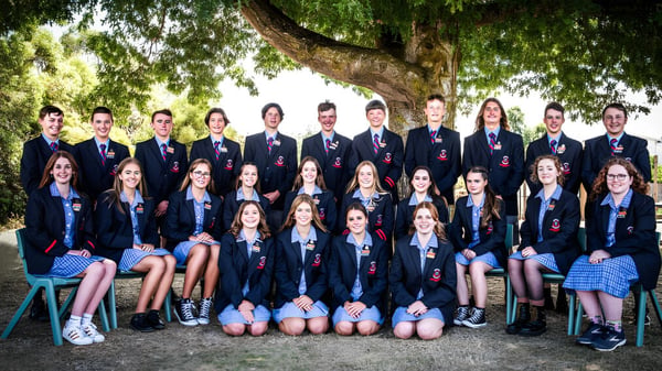 Eine Gruppe Schüler der Queechy High School steht zusammen unter einem großen Baum in einem parkähnlichen Gelände.